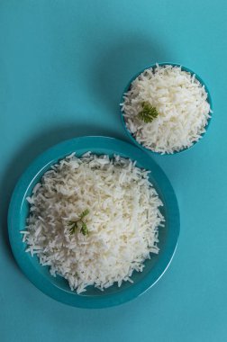 Düz beyaz basmati pirinç bir mavi plaka ve mavi arka plan üzerinde kase pişmiş