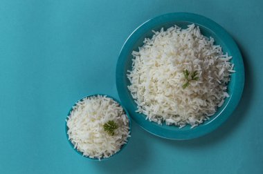 Düz beyaz basmati pirinç bir mavi plaka ve mavi arka plan üzerinde kase pişmiş