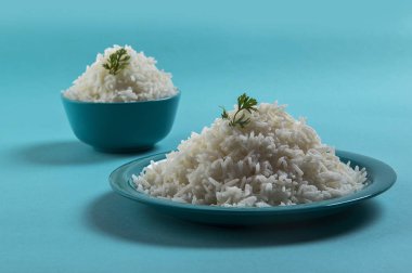 Düz beyaz basmati pirinç bir mavi plaka ve mavi arka plan üzerinde kase pişmiş