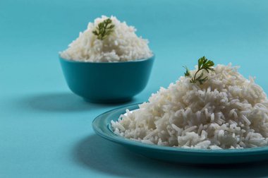 Düz beyaz basmati pirinç bir mavi plaka ve mavi arka plan üzerinde kase pişmiş