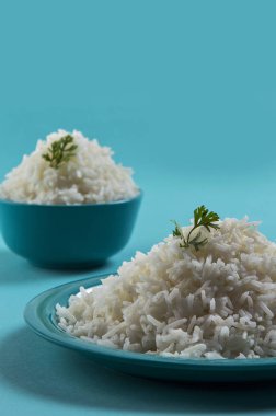 Düz beyaz basmati pirinç bir mavi plaka ve mavi arka plan üzerinde kase pişmiş