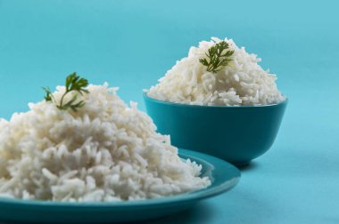 Düz beyaz basmati pirinç bir mavi plaka ve mavi arka plan üzerinde kase pişmiş