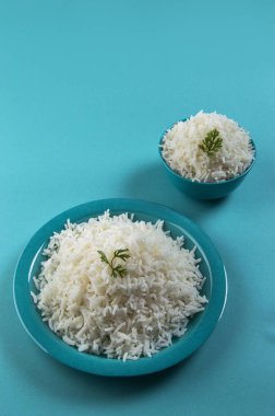Düz beyaz basmati pirinç bir mavi plaka ve mavi arka plan üzerinde kase pişmiş