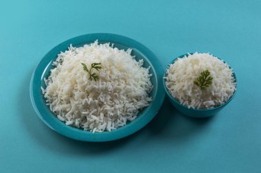 Düz beyaz basmati pirinç bir mavi plaka ve mavi arka plan üzerinde kase pişmiş