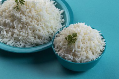 Düz beyaz basmati pirinç bir mavi plaka ve mavi arka plan üzerinde kase pişmiş