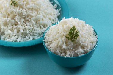 Düz beyaz basmati pirinç bir mavi plaka ve mavi arka plan üzerinde kase pişmiş