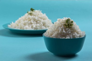 Düz beyaz basmati pirinç bir mavi plaka ve mavi arka plan üzerinde kase pişmiş