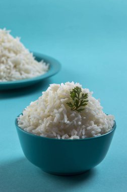Düz beyaz basmati pirinç bir mavi plaka ve mavi arka plan üzerinde kase pişmiş