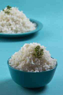 Düz beyaz basmati pirinç bir mavi plaka ve mavi arka plan üzerinde kase pişmiş