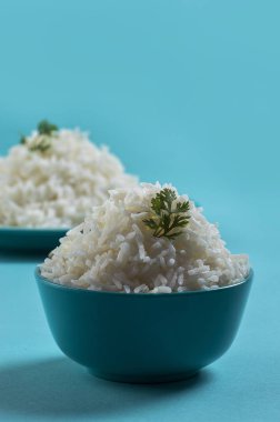 Düz beyaz basmati pirinç bir mavi plaka ve mavi arka plan üzerinde kase pişmiş