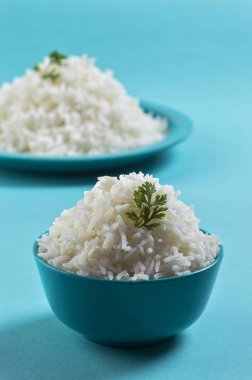 Düz beyaz basmati pirinç bir mavi plaka ve mavi arka plan üzerinde kase pişmiş