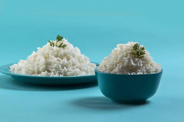 Cooked plain white basmati rice in a blue plate and bowl on blue background — Stock Photo, Image