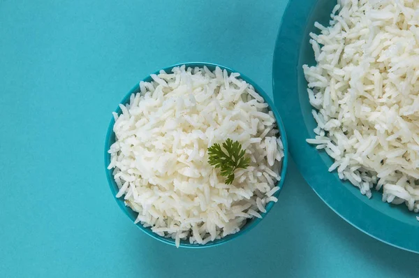 Düz beyaz basmati pirinç bir mavi plaka ve mavi arka plan üzerinde kase pişmiş
