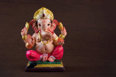 Hindu God Ganesha. Ganesha Idol on dark wooden background. clipart