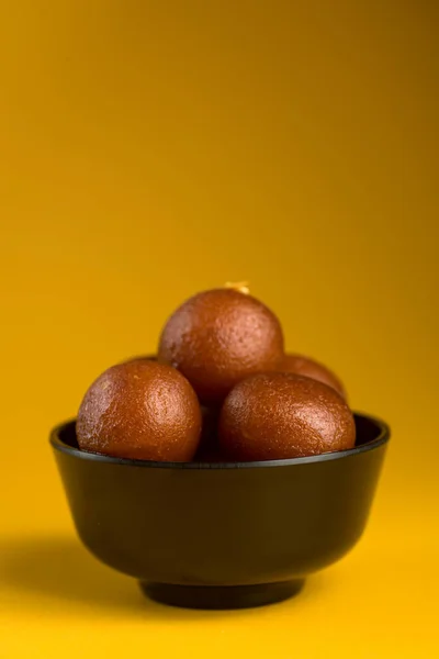 Indisches Dessert oder süßes Gericht: Gulab Jamun in Schüssel auf gelbem Hintergrund. — Stockfoto