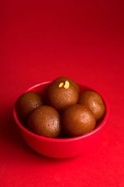 Gulab jamun in roter Schüssel auf rotem Hintergrund. indisches Dessert oder süßes Gericht. — Stockfoto