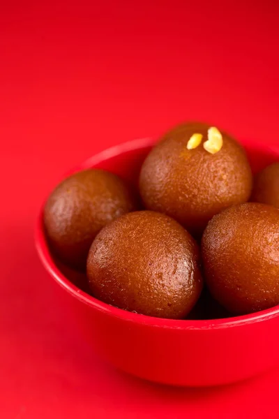 Gulab jamun in roter Schüssel auf rotem Hintergrund. indisches Dessert oder süßes Gericht. — Stockfoto