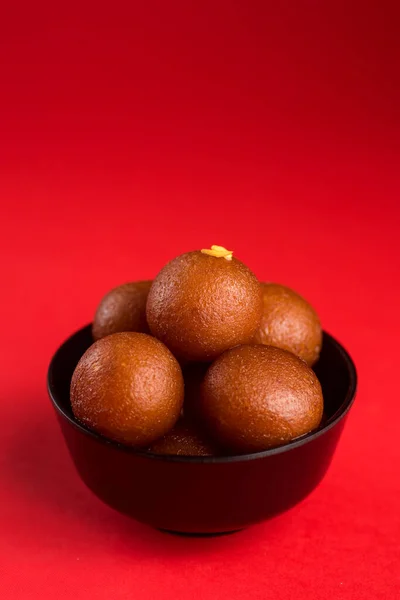 Gulab jamun in schwarzer Schüssel auf rotem Hintergrund. indisches Dessert oder süßes Gericht. — Stockfoto