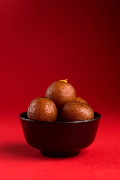 Gulab Jamun in ciotola nera su sfondo rosso. Dessert indiano o piatto dolce . — Foto Stock