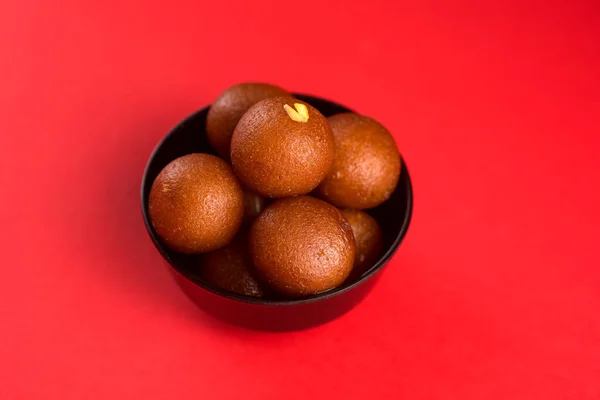 Gulab Jamun in zwarte schaal op rode achtergrond. Indiase dessert of zoete schotel. — Stockfoto