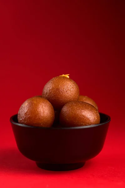 Gulab jamun in schwarzer Schüssel auf rotem Hintergrund. indisches Dessert oder süßes Gericht. — Stockfoto