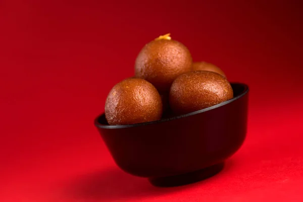 Gulab Jamun in ciotola nera su sfondo rosso. Dessert indiano o piatto dolce . — Foto Stock