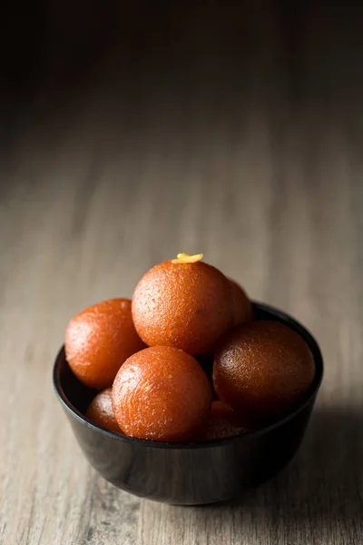 Indisches Dessert oder süßes Gericht: Gulab Jamun in Schale auf Holzgrund. — Stockfoto