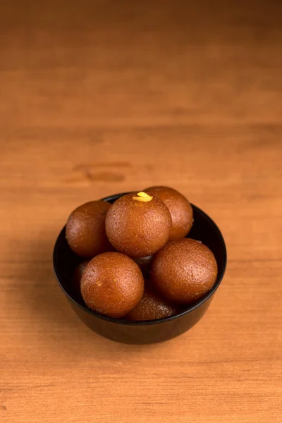 Indisches Dessert oder süßes Gericht: Gulab Jamun in Schale auf Holzgrund. — Stockfoto