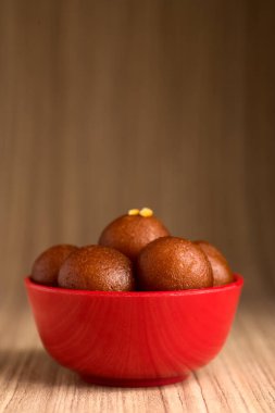 Ahşap arka planda kırmızı kasede Gulab Jamun. Hint Tatlısı ya da Tatlı Tabak.