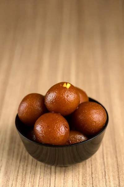 Indisches Dessert oder süßes Gericht: Gulab Jamun in Schale auf Holzgrund. — Stockfoto