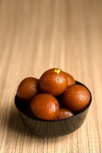 ของหวานอินเดียหรืออาหารหวาน: Gulab Jamun ในชามบนพื้นหลังไม้ . — ภาพถ่ายสต็อก