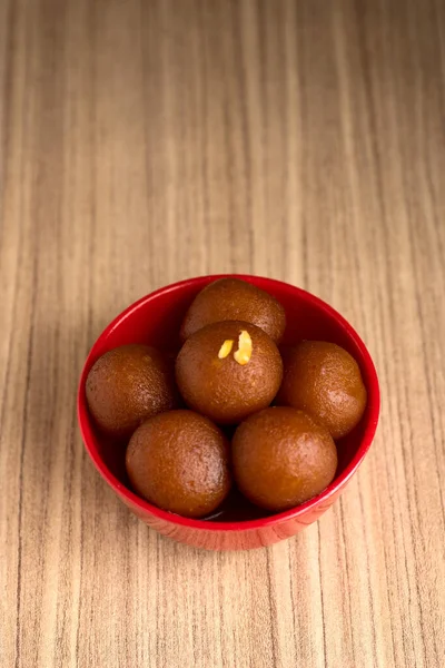 Gulab jamun in roter Schale auf Holzgrund. indisches Dessert oder süßes Gericht. — Stockfoto