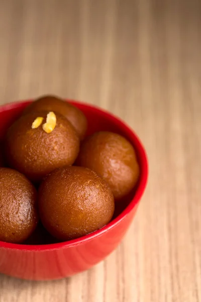 Gulab jamun in roter Schale auf Holzgrund. indisches Dessert oder süßes Gericht. — Stockfoto