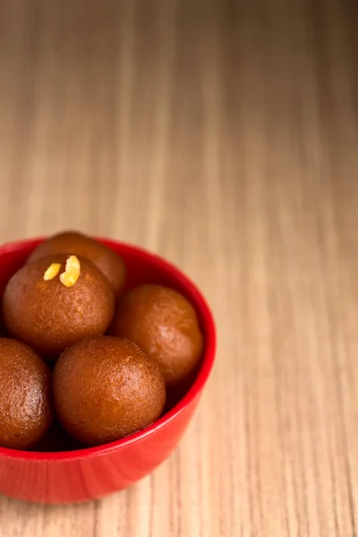 Gulab jamun in roter Schale auf Holzgrund. indisches Dessert oder süßes Gericht. — Stockfoto