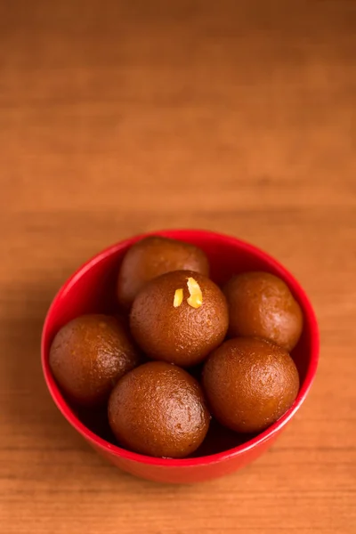 Gulab jamun in roter Schale auf Holzgrund. indisches Dessert oder süßes Gericht. — Stockfoto