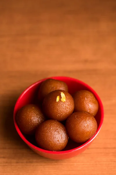 Gulab Jamun en tazón rojo sobre fondo de madera. Postre indio o plato dulce . —  Fotos de Stock