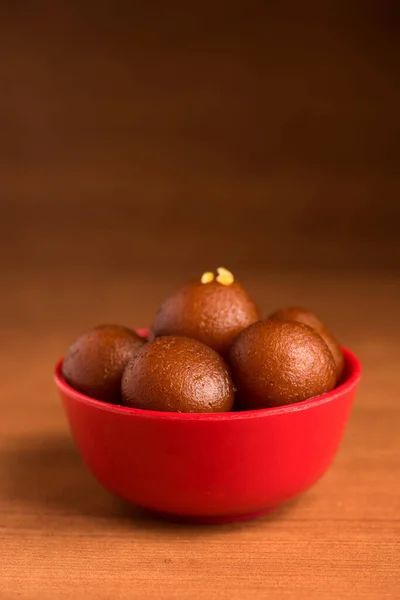 Gulab jamun in roter Schale auf Holzgrund. indisches Dessert oder süßes Gericht. — Stockfoto