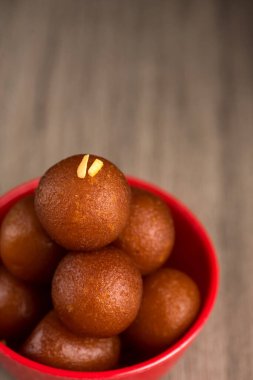 Ahşap arka planda kırmızı kasede Gulab Jamun. Hint Tatlısı ya da Tatlı Tabak.