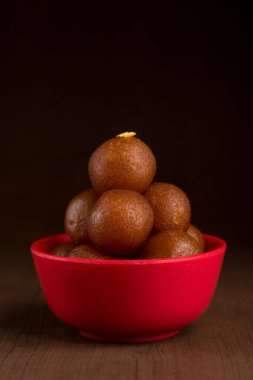 Ahşap arka planda kırmızı kasede Gulab Jamun. Hint Tatlısı ya da Tatlı Tabak.