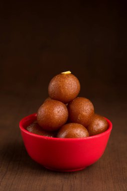 Ahşap arka planda kırmızı kasede Gulab Jamun. Hint Tatlısı ya da Tatlı Tabak.