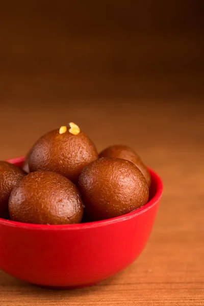 Gulab jamun in roter Schale auf Holzgrund. indisches Dessert oder süßes Gericht. — Stockfoto