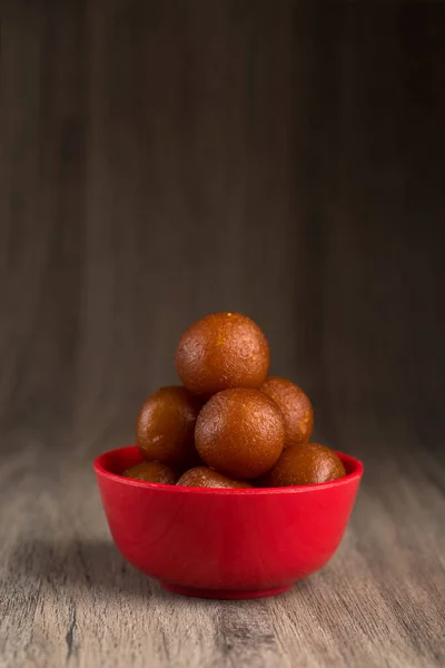 Gulab jamun in roter Schale auf Holzgrund. indisches Dessert oder süßes Gericht. — Stockfoto