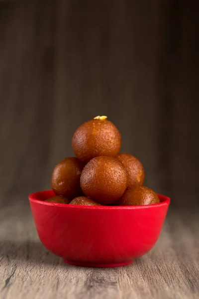 Gulab jamun in roter Schale auf Holzgrund. indisches Dessert oder süßes Gericht. — Stockfoto