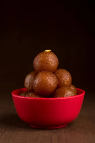 Gulab jamun in roter Schale auf Holzgrund. indisches Dessert oder süßes Gericht. — Stockfoto