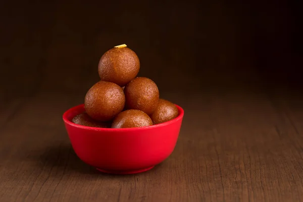 Гулаб Джамун в красной чаше на деревянном фоне. Индийский десерт или сладкое блюдо . — стоковое фото