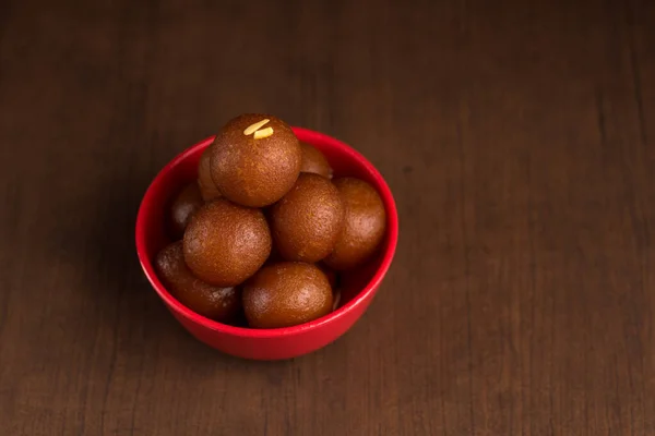 Gulab jamun in roter Schale auf Holzgrund. indisches Dessert oder süßes Gericht. — Stockfoto