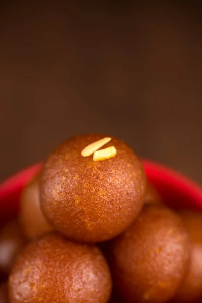 Gulab jamun in roter Schale auf Holzgrund. indisches Dessert oder süßes Gericht. — Stockfoto