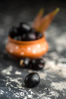 Jambolan eriği veya jambul veya Jamun meyvesi, taş desenli arka planda yaprağı olan Java eriği (Syzygium cumini).