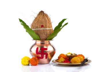 Hindistan cevizi ve mango yaprağıyla bakır Kalaş ve beyaz arka planda çiçek desenli diya, kumkum ve tatlılar ile pooja thali. Hindu pujası için gerekli..