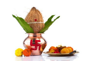 Hindistan cevizi ve mango yaprağıyla bakır Kalaş ve beyaz arka planda çiçek desenli diya, kumkum ve tatlılar ile pooja thali. Hindu pujası için gerekli..